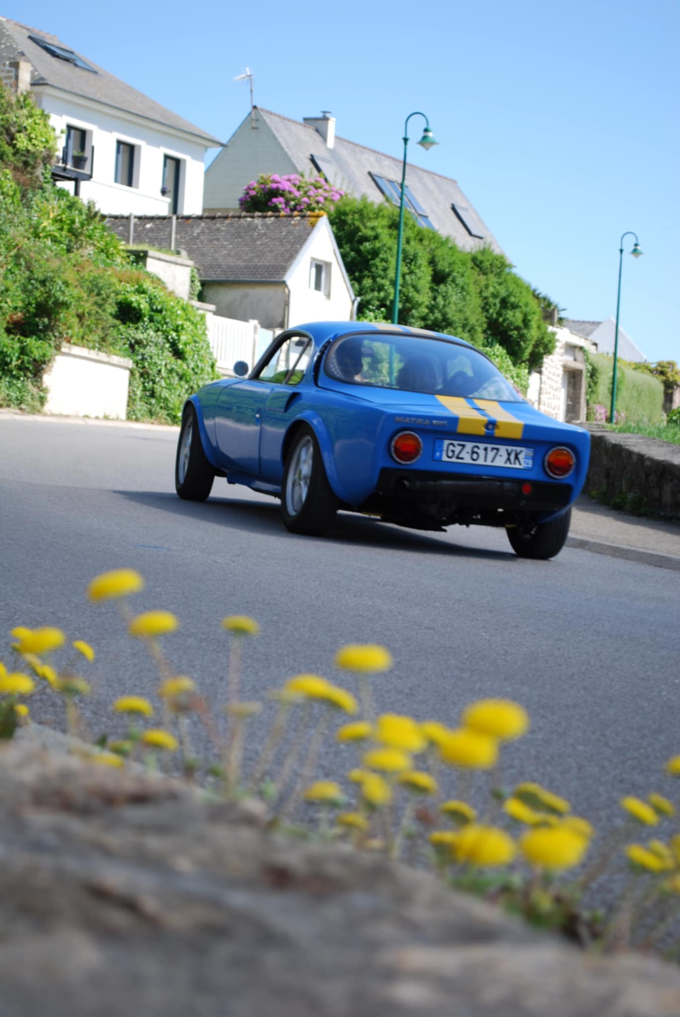 Voiture classique vintage garée dans un décor breton avec végétation et murs en pierre